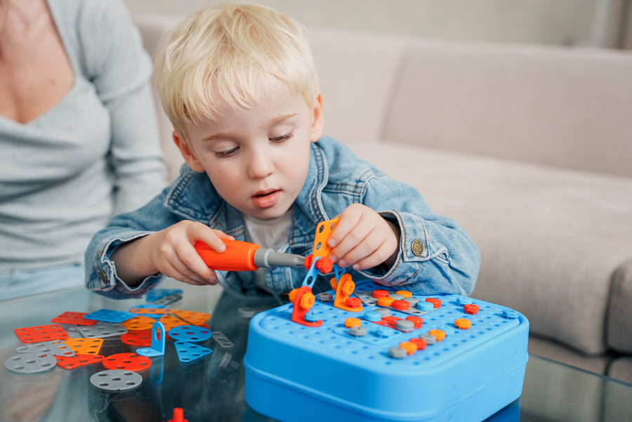 Dreng skruer en del fast med den orange skruetrækker